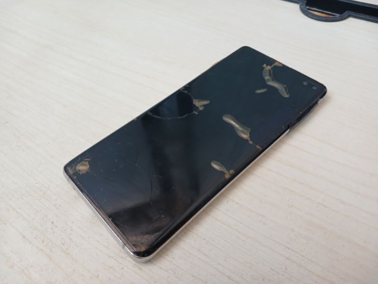 A non-functioning phone on a light-coloured table. It stopped working two months ago, and its screen shows the damage