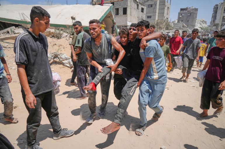 Palestinians carry a wounded man who was injured while rushing to collect humanitarian aid airdropped by parachute into Gaza City, in the northern Gaza Strip, Thursday, Aug. 7, 2025. (AP Photo/Jehad Alshrafi)