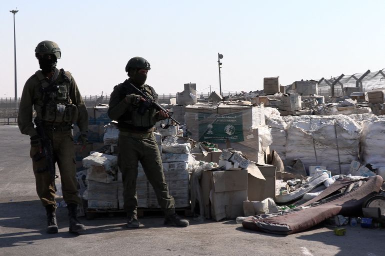 PHOTO TAKEN DURING A CONTROLLED EMBED TOUR WITH THE ISRAELI ARMY AND SUBSEQUENTLY EDITED UNDER MILITARY SUPERVISION -- Israeli soldiers stand guard next to humanitarian aid at the Kerem Shalom crossing between southern Israel and the Gaza Strip on July 27, 2025. (Photo by Carlos REYES / AFP)