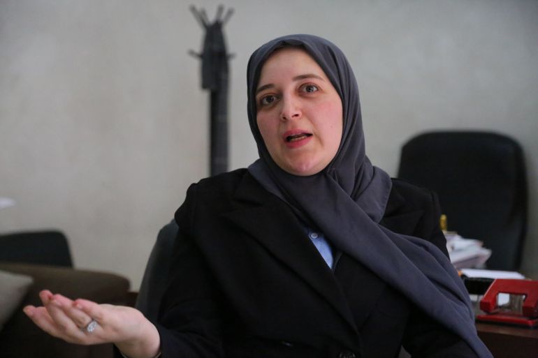 Kind-looking woman in a grey hijab gestures as she speaks