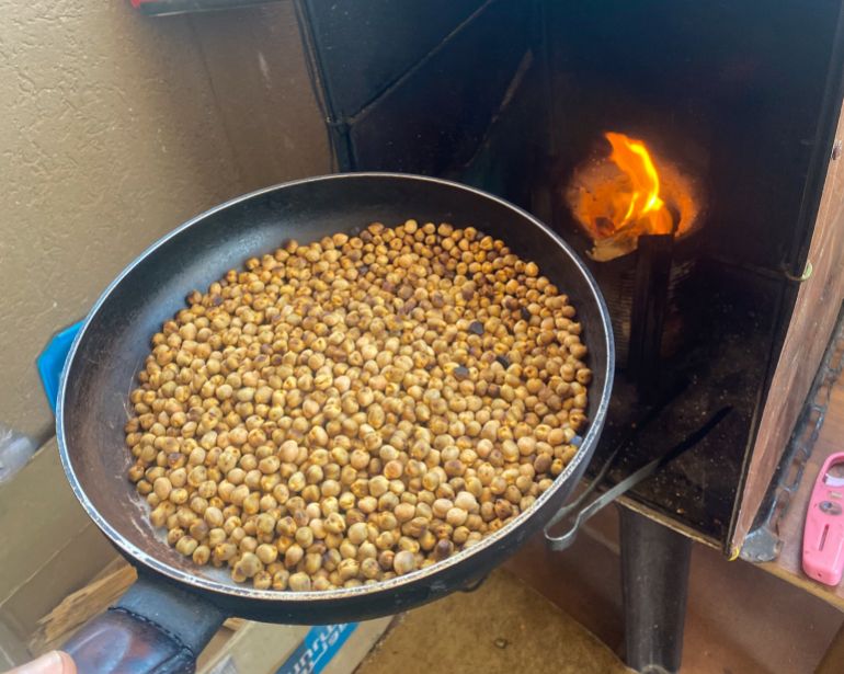 A pan of chickpeas going into an open-flame oven to be roasted