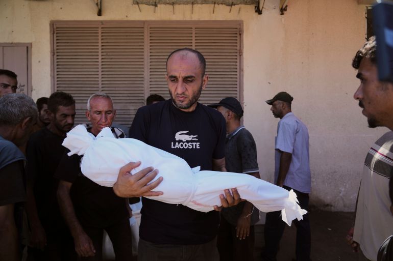 A man carries the body of 3-year-old Palestinian child Nour Abu Ouda, killed in an Israeli airstrike on the Gaza Strip, at Al-Aqsa Hospital in Deir al-Balah, Sunday, Sept. 14, 2025. (AP Photo/Abdel Kareem Hana)