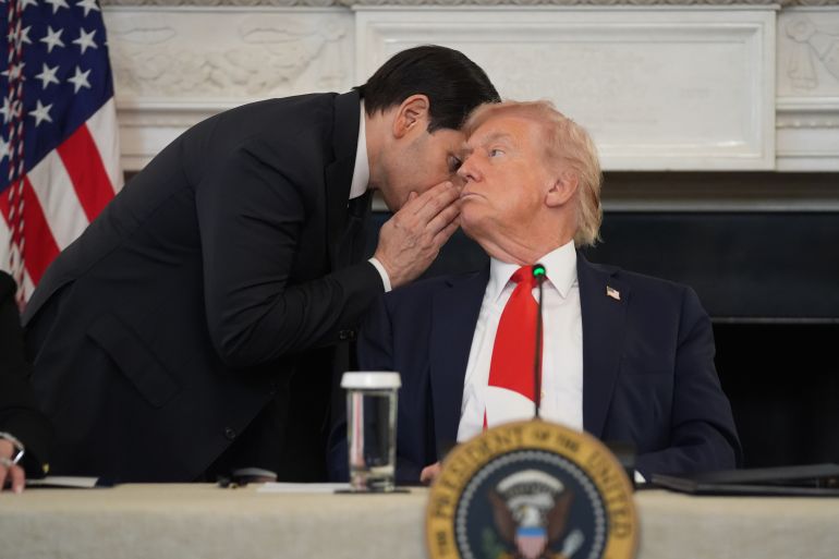 Marco Rubio leans over to whisper in Donald Trump's ear at a roundtable he's seated at.