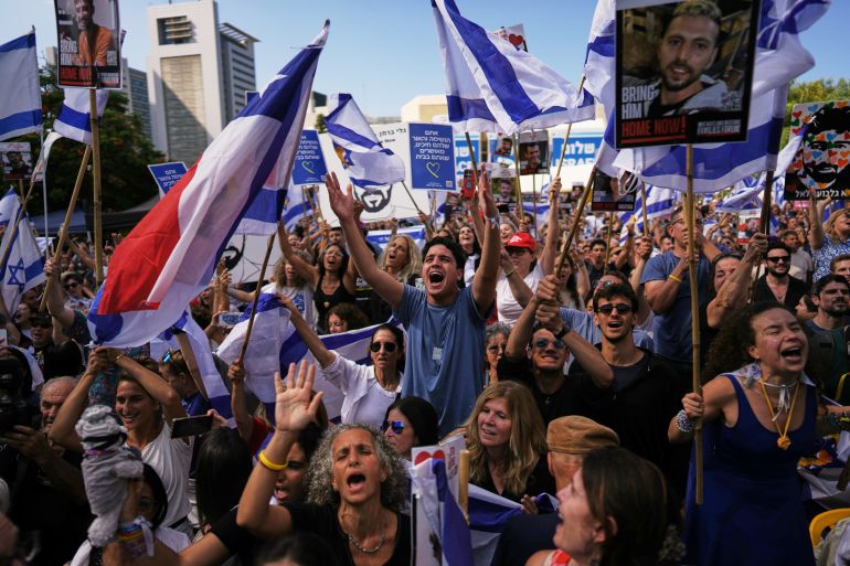 People react as they gather to watch a live broadcast of Israeli hostages released from Gaza at a plaza known as hostages square in Tel Aviv, Israel, Monday, Oct. 13, 2025. The release took place as part of a cease-fire agreement between Israel and Hamas. (AP Photo/Oded Balilty)