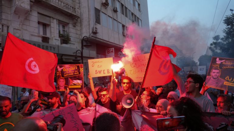 A man holds a flare as protesters rally.