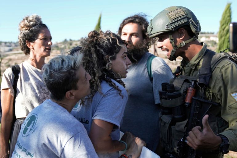 Israeli activists surround Alice Kisiya, center, as they try to enter her family's land, after the Palestinian family was forcefully evicted by Israeli settlers backed by soldiers who declared it a closed military area, in the West Bank town of Beit Jala, Friday, Aug. 2, 2024. (AP Photo/Mahmoud Illean)