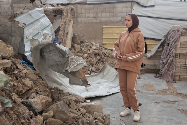 Batoul stands in front of the rubble of her destroyed home, where she was trapped for about an hour before being rescued when it was hit [Abdelhakim Abu Riash/ media]
