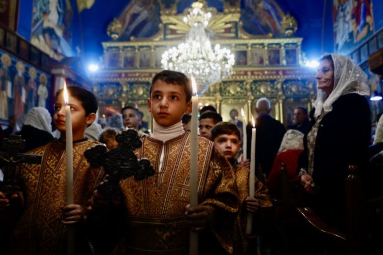 Altar boys carry candles as Christian worshippers attend a Christmas service at the Greek Orthodox Church of Saint Porphyrius in the Old City of Gaza City on January 7, 2026. (Photo by Omar AL-QATTAA / AFP)