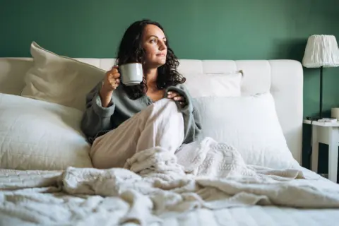 Getty Images A woman in bed drinking a cup of tea