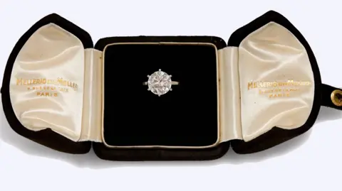 Millon A large round diamond ring is seen displayed in an open black velvet ring case 