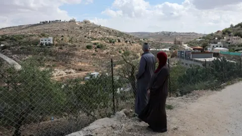 Reuters Mahmoud al-Tubasi and his wife Aedah look at their home, which was damaged during an Israeli settler attack, in Jalud, in the occupied West Bank (29 September 2026)