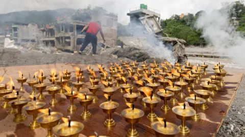 EPA Oil lamps burn as Buddhist monks perform a 13th-day ritual in front of a house damaged by flash floods.