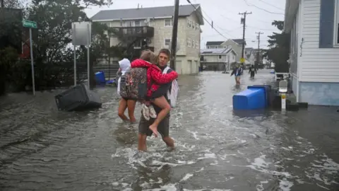 Reuters People walk in flooded streets in Surf City, New Jersey, on 26 September 2026