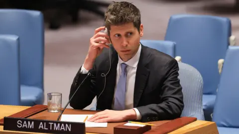 Reuters Sam Altman of OpenAI sitting before the US Security Council wearing a suit and tie while listening to a translation of comments.