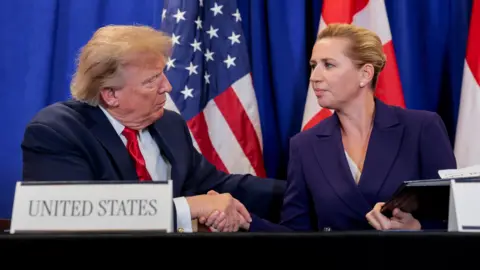 Reuters US President Donald Trump shakes hands with Danish Prime Minister Mette Frederiksen as they attend a trilateral signing event