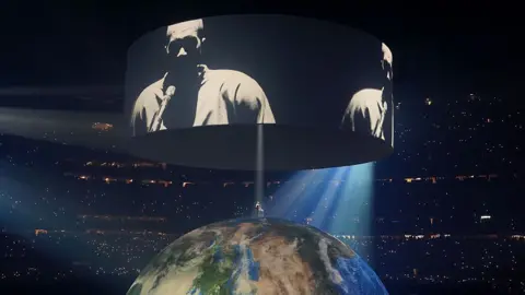 Getty Images Kanye West performing in New Orleans. Ye stands atop an enormous globe, a spotlight beaming down on him. Above he is projected on screens to a crowd that surrounds him. 