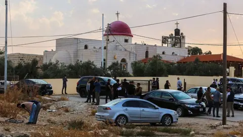 Getty Images Security officials and public outside Greek Orthodox church where attack happened in Jordan. 
