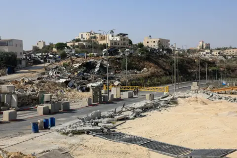 Reuters Sandy land around checkpoint. Wreckage in the distance. 