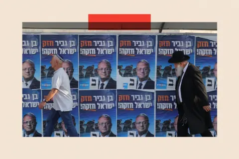 EPA Two men walk past posters bearing Itamar Ben-Gvir's face