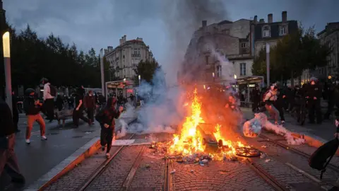 EPA People clash with police officers as objects burn at a barricade during a demonstration against the high cost of living in Bordeaux, France, 24 October 2026.