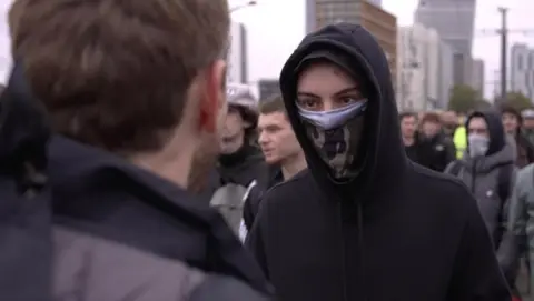 A masked teenage protester talks to a BBC correspondent in Paris. Photo: 24 October 2026