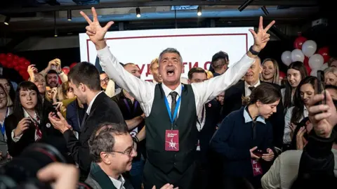 Getty Images A man in a waistcoat and grey hair celebrates