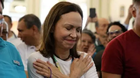 Reuters A woman in white crosses her arms on her chest with her hands pointed towards her shoulders and her eyes closed