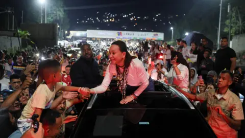 Reuters Maria Corina Machado reaches from the top of a car to hold a young boy's hand