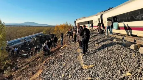 1vanta3 / X via Anadolu / Getty Images Wide shot showing a derailed train carriage in an embankment