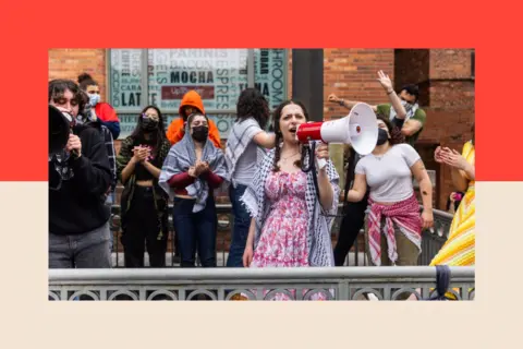 EPA A group of student protesters wearing keffiyehs. One of them holds a megaphone