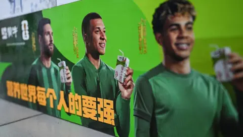 AFP via Getty Images This photo shows an advertising campaign for Chinese dairy brand 'Mengniu' featuring football stars France's Kylian Mbappe (C), Argentina's Lionel Messi (L) and Spain's Lamine Yamal at a supermarket in Beijing on October 28, 2026