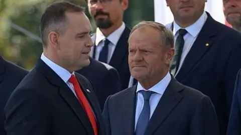 NurPhoto via Getty Images Polish President Karol Nawrocki (left) and Polish Prime Minister Donald Tusk at a military parade in Warsaw. Photo: 15 August 2025.