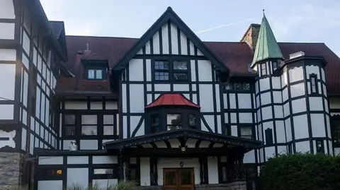 Getty Images A large, black and white white multi-storey house with a red tiled roof. 