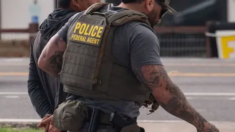 Getty Images An ICE agent with a man in handcuffs