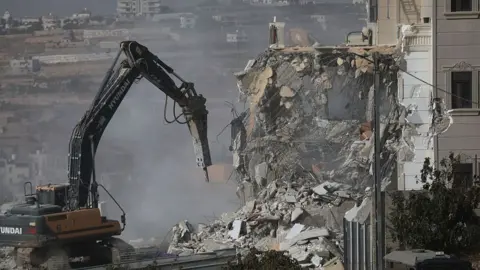 Anadolu via Getty Images Digger destroys house. Rubble, dust and concrete. 