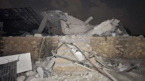 Anadolu via Getty Images Rubble sits atop a small brick wall and six stairs.