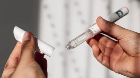 Getty Images A womans hands hold a weight loss injection pen.
