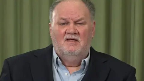 ITV/Shutterstock Thomas Markle, an older white man with grey hair and a short white beard. He is wearing a dark blue suit jacket and light blue shirt.