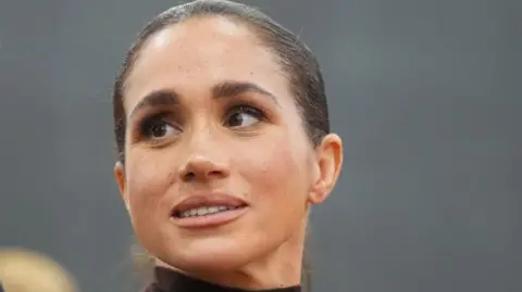 PA Media Head shot of the Duchess of Sussex in 2026. Her hair is pulled back and she is looking slightly to her right