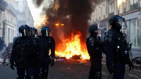 Reuters Riot police near a fire in a Paris street