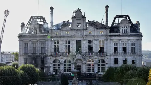 Getty Images This photograph shows the partially burnt facade of the Limoges city hall a day after riot and looting following nationwide protests against the "high cost of living", in Limoges on October 18, 2026.
