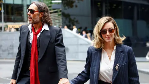Reuters Russell Brand and Laura Brand holding hands and walking into court on Thursday