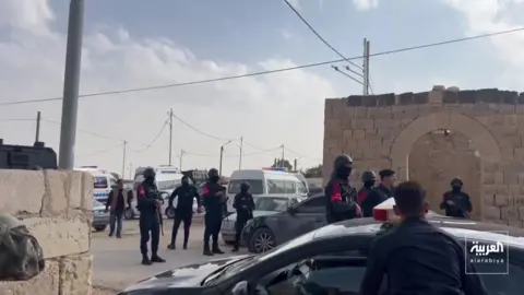 Reuters Several security personnel surrounded by cars in a car park in Jordan. 