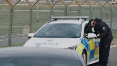 PA Man looking in a police car at RAF Fairford
