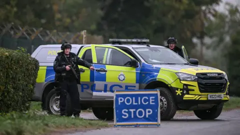 Getty Images Two armed police officers posted outside RAF Fairford base on September 27. There is a police car, a police stop sign and two officers looking straight ahead