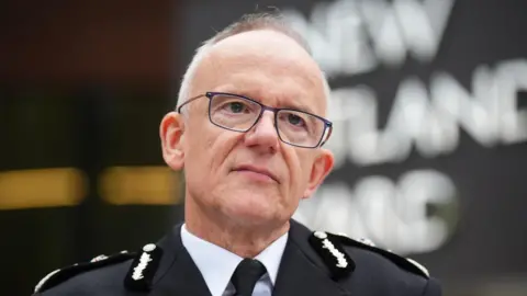 PA Media Metropolitan Police Commissioner Sir Mark Rowley stands in front of the New Scotland Yard sign, his head and shoulders in shot